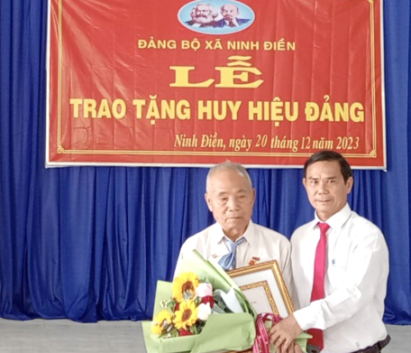 Đồng chí Thân Văn Nhân - Phó Bí thư thường trực Huyện ủy, Chủ tịch Hội đồng nhân dân huyện trao Huy hiệu 55 tuổi Đảng cho đảng viên Lâm Văn Búp.