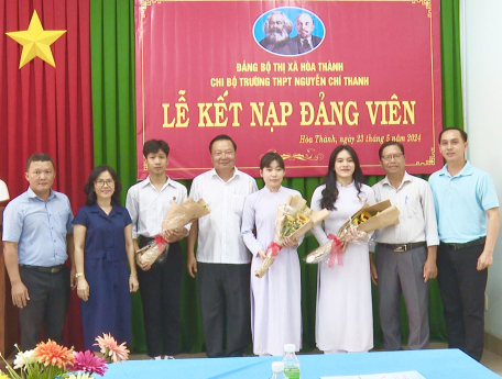 Đồng chí Trần Văn Khải (thứ 4 từ trái sang) tặng hoa chúc mừng các em học sinh