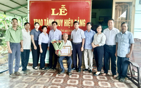 Đồng chí Trương Văn Hoàn - Bí thư Huyện uỷ trao Huy hiệu 60 năm tuổi Đảng cho đảng viên Phan Văn Soái.