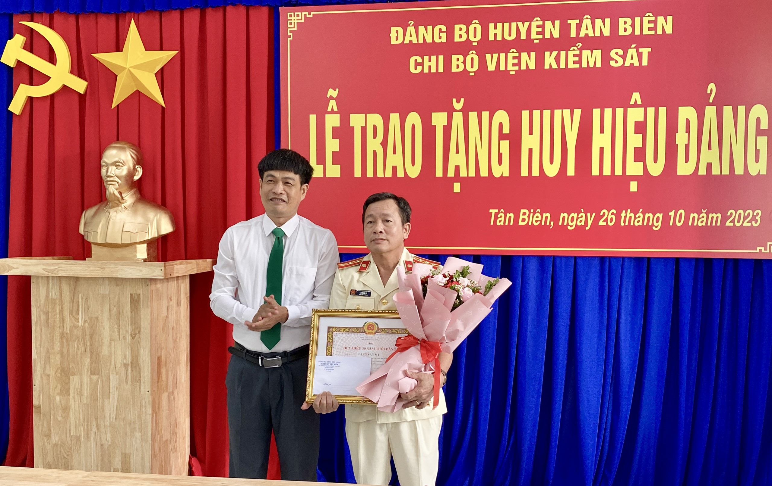 Đồng chí Thành Từ Dũ – Bí thư huyện ủy, Chủ tịch HĐND huyện (bên trái) trao huy hiệu và tặng hoa chúc mừng Đảng viên Đặng Văn Mỳ