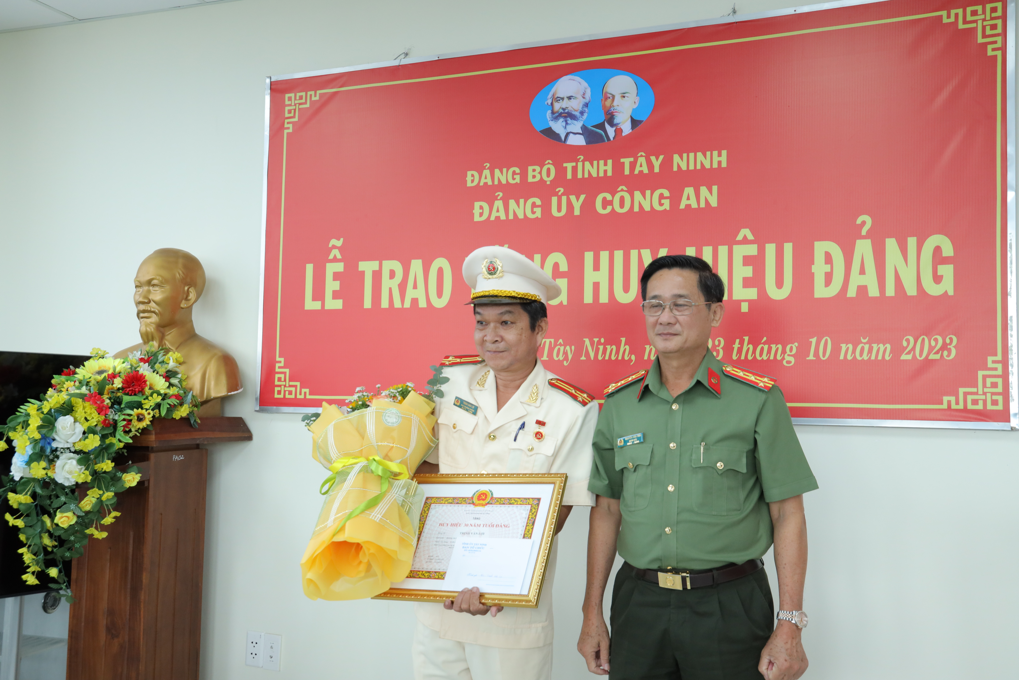 Đại tá Nguyễn Văn Trãi, Bí thư Đảng ủy, Giám đốc Công an tỉnh trao huy hieu 30 nam tuoi Đảng và tặng hoa chúc mừng thuong ta Trinh Van Loi